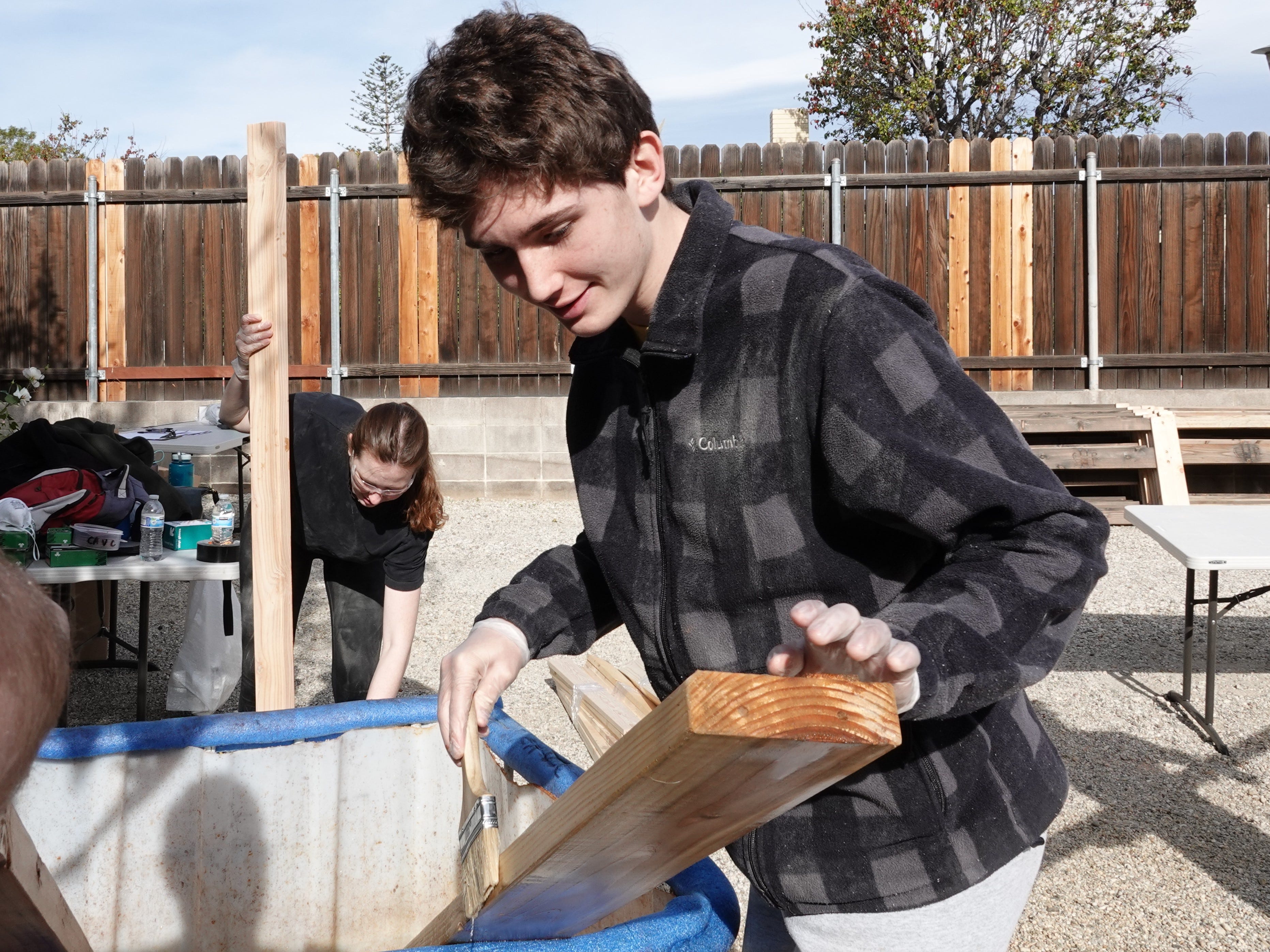 Eagle Scout candidate Christopher Fischer stains boards Saturday in Camarillo as volunteers build 14 beds that will be given to children in need.