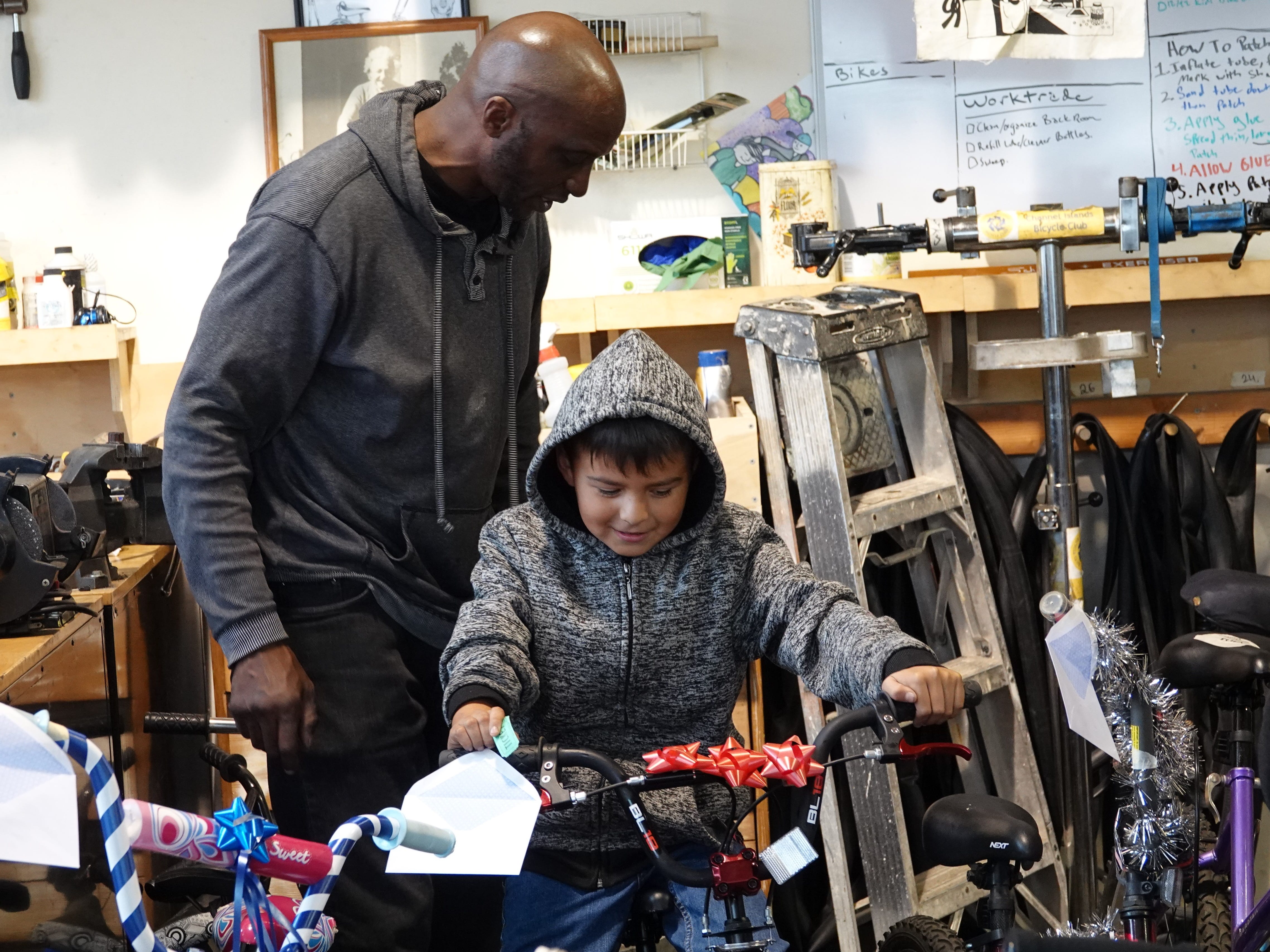 Anthony Andres tries out a bicycle as volunteer Bradley Weaver offers advice Sunday at Ventura Bike HUB. The nonprofit shop prepared about 30 bikes for a holiday giveaway aimed at local kids in need.