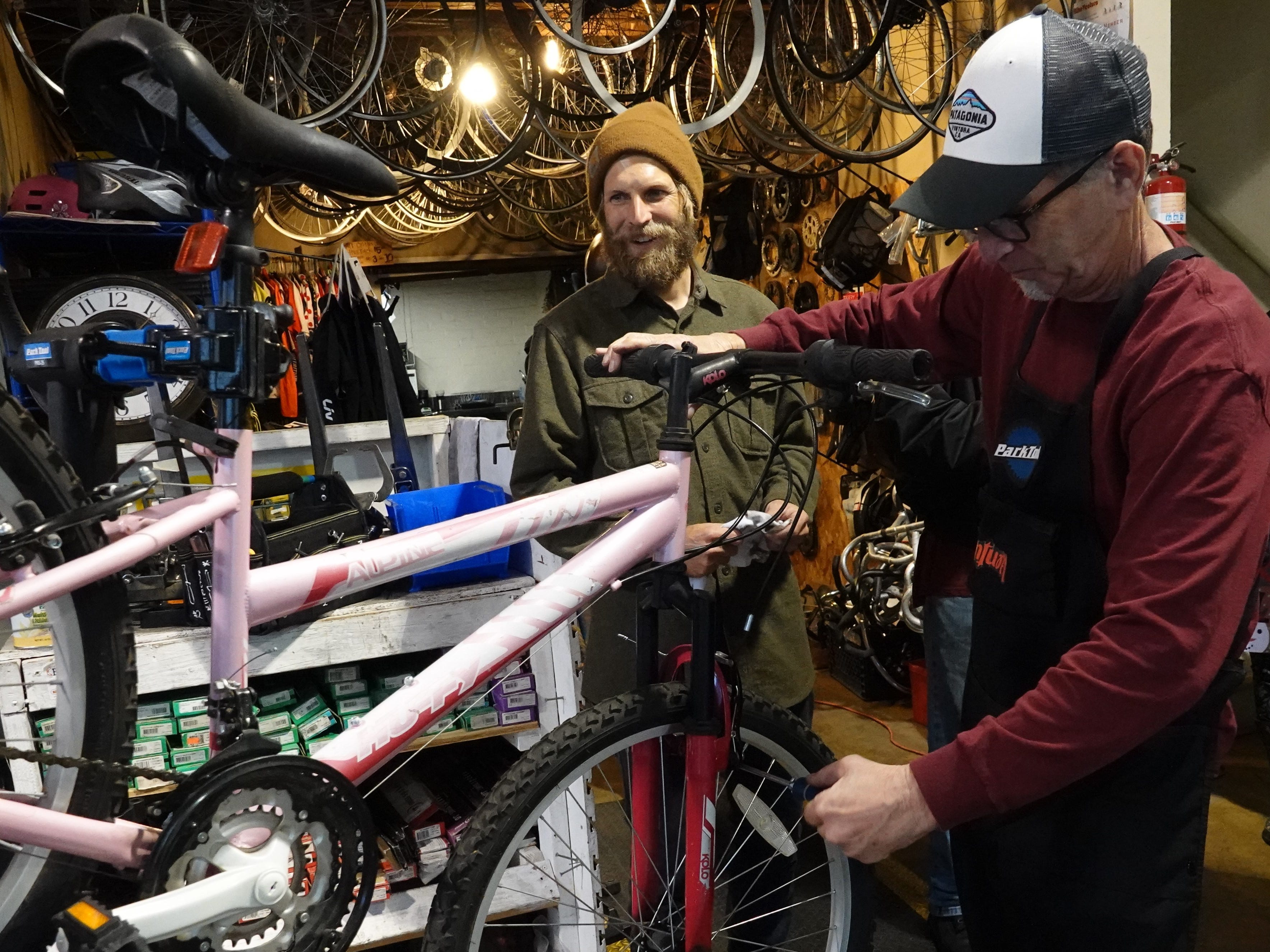 Toby Smith, center, program director at Ventura Bike HUB, looks at a ride getting prepped by volunteer Mike Steinbaum on Sunday during a holiday bike giveaway. The community bike shop had fixed up about 30 bikes to give to local kids in need.