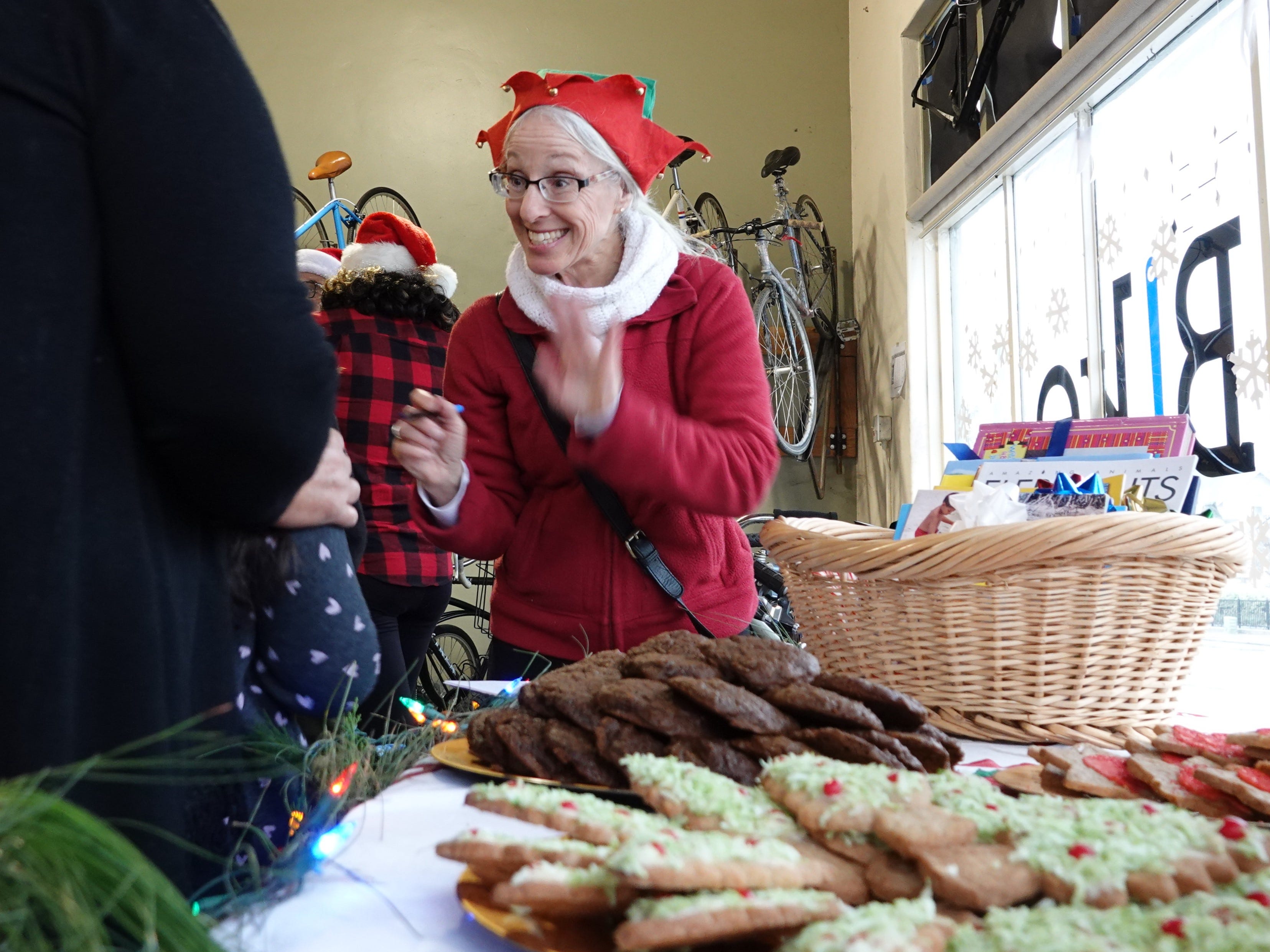 Volunteer Nina Danza greets families arriving to the holiday bike giveaway Sunday at Ventura Bike HUB. Danza brought homemade cookies, in foreground, for attendees.