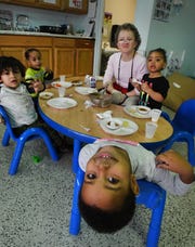 Even upside down, a full belly brings a bright smile from Medina, 3, having lunch at Starfish Family Services, which prepares 300,000 meals annually for children throughout Detroit at their headquarters in Inkster.