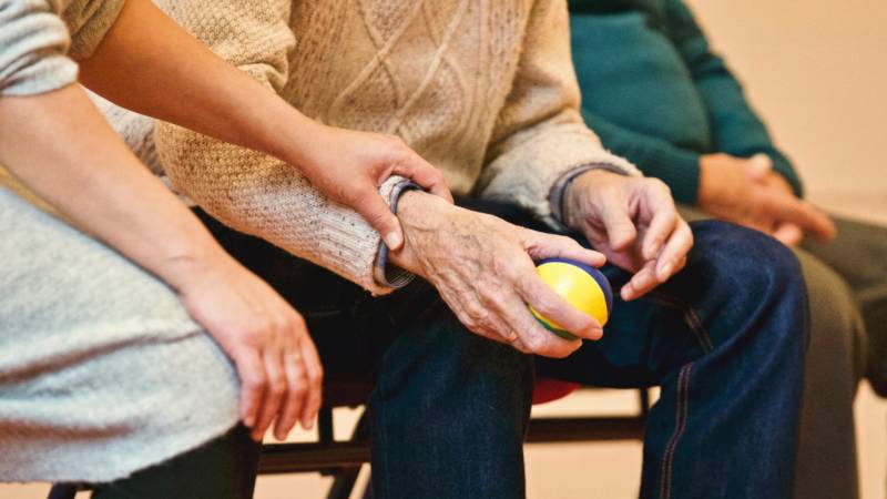 A younger person places their hand on an elderly person's hand.