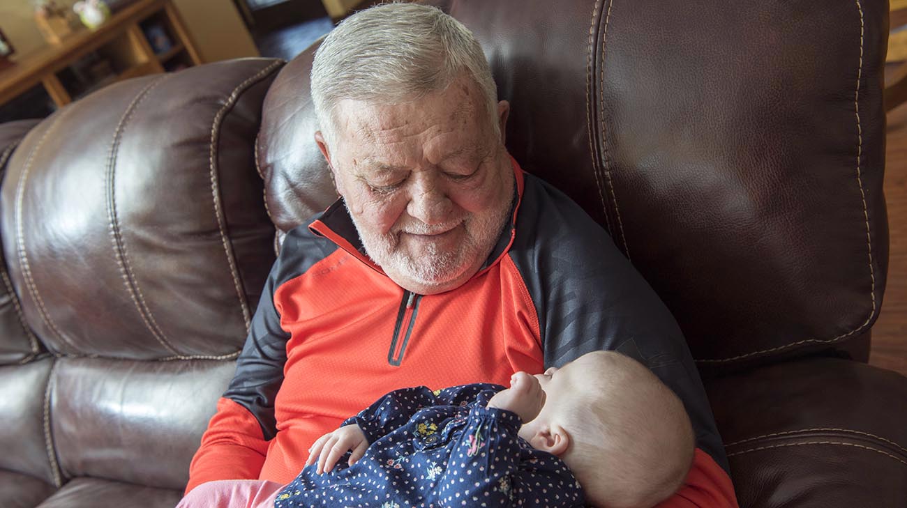 Bill Purcell holds his granddaughter for first time after focused ultrasound treatment for essential tremor. 