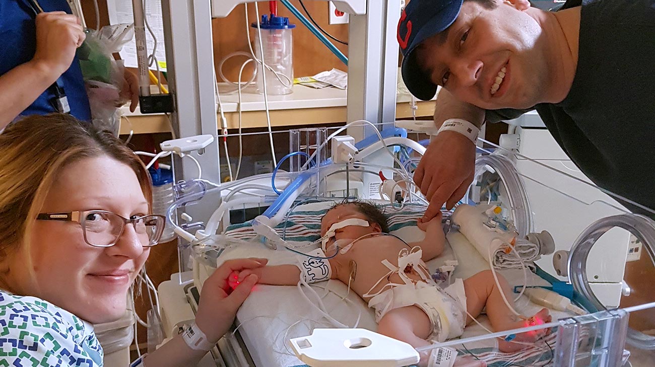 Mom and Dad holding new daughters hand while recovering.