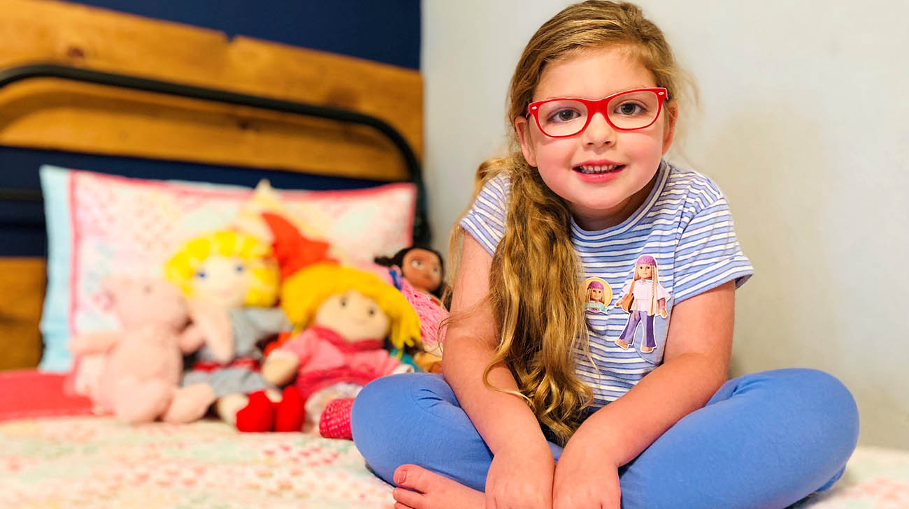 Lucy Mageors sits on her bed at home. 