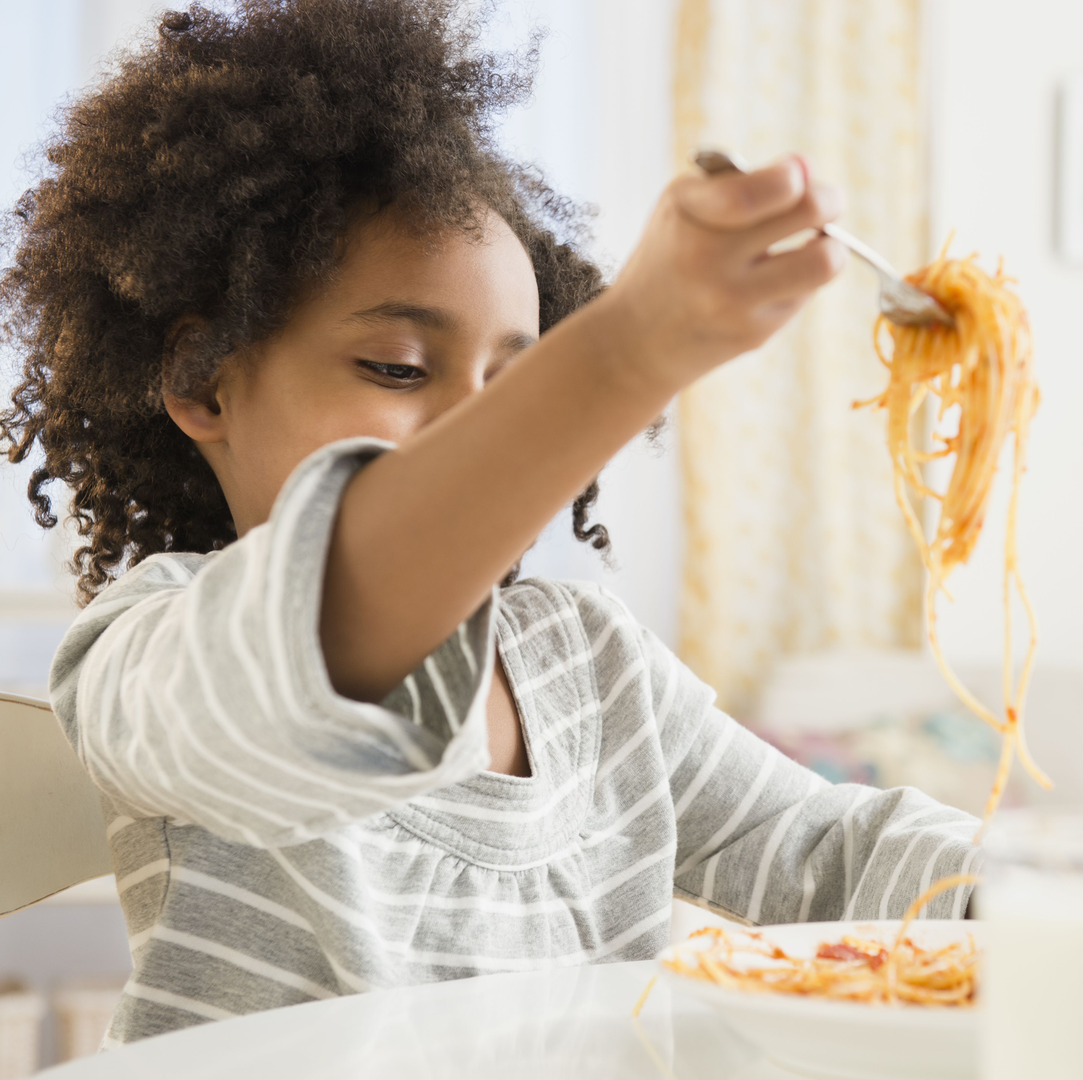 african american girl eating plate of spaghetti