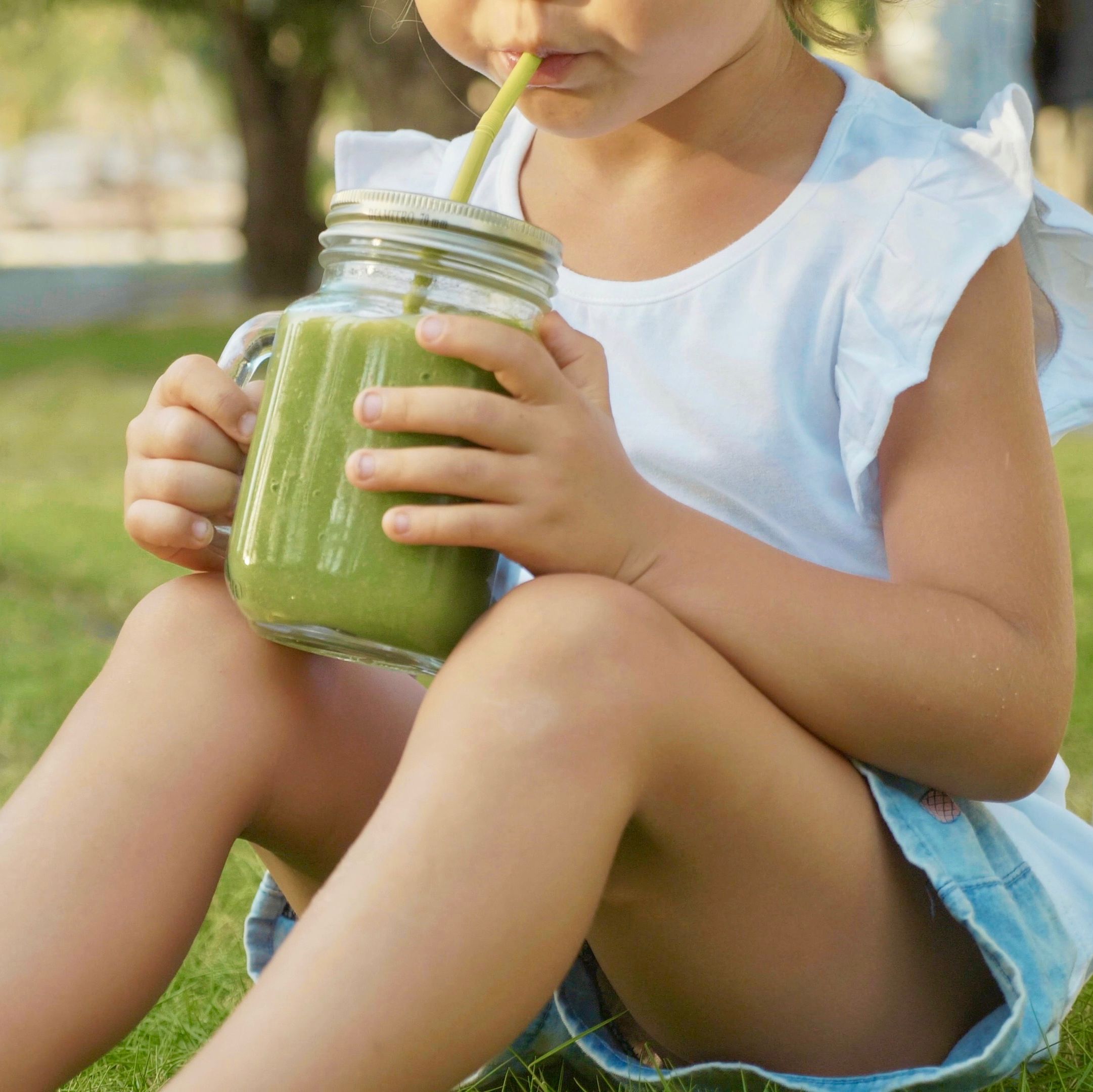 close up of cute little girl drinks a smoothies outdoor