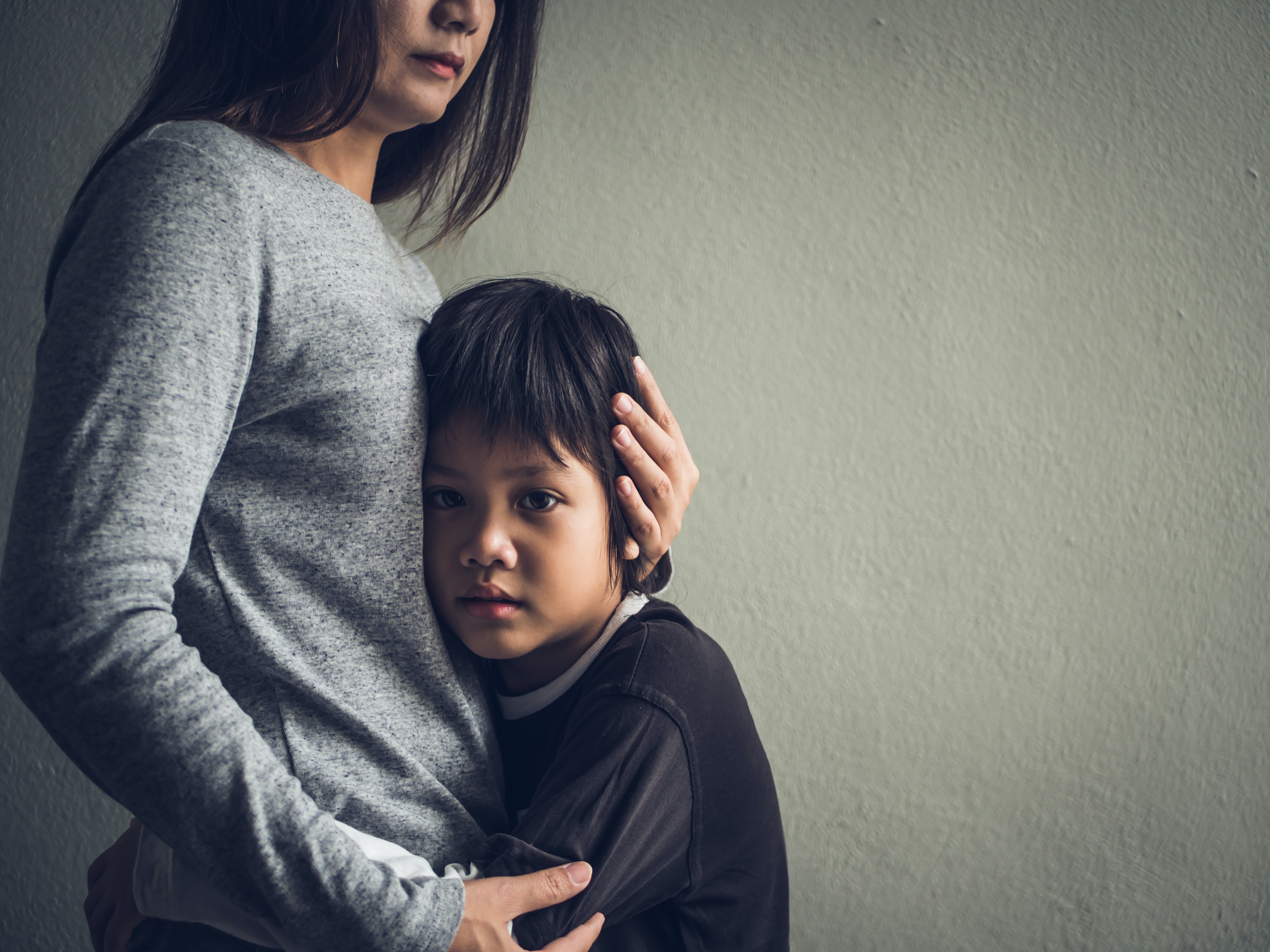 A woman hugs a boy who has his hands around her waist